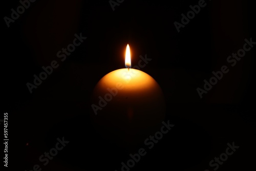 One round burning candle on black background