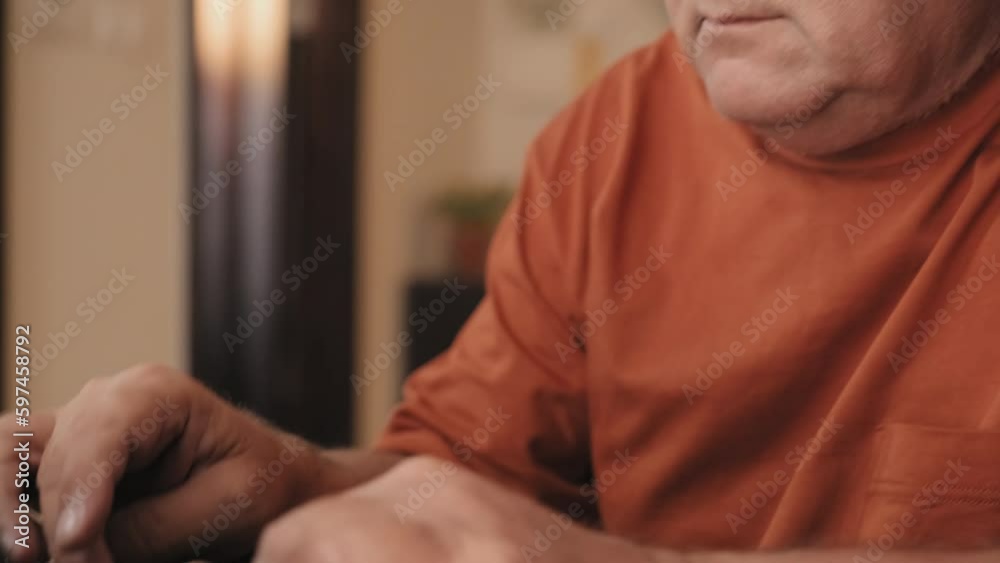 Close up tilt down shot of elderly man in eyeglasses typing laptop at desk while working or studying remotely at home Close up tilt down shot of elderly man in eyeglasses typing laptop at desk while working or studying remotely at home