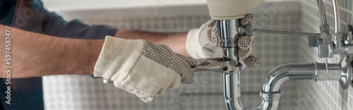 Handyman is repairing faucet of a sink at bathroom. Maintenance and household assistance concept photo