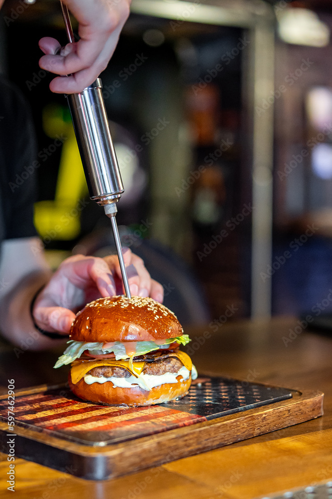 chef adds cheese sauce to the burger with a syringe Stock Photo Adobe