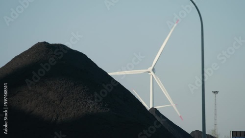 Pile of black coal stones next to wind turbines