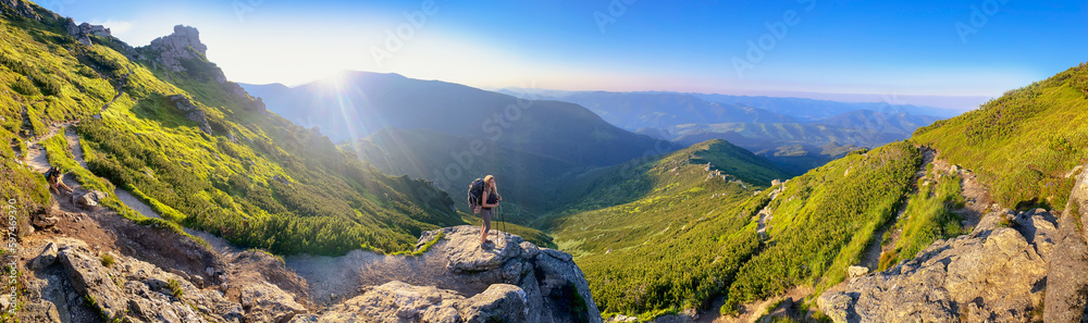 Young woman and her dog on mount Vuhaty Kamin. Panorama. Chornohora ridge, Carpathian mountains, Ukraine.