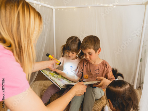 niño y niña leyendo un libro con linterna 