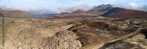 A view of the dirt road stretching to the horizon among the lava fields. Top view, photo taken from the drone. Helgafellssveit, Iceland.