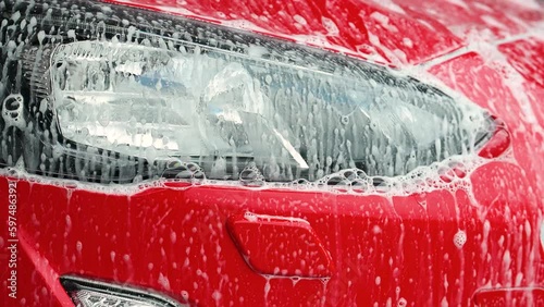 Headlamp of a red car being washed