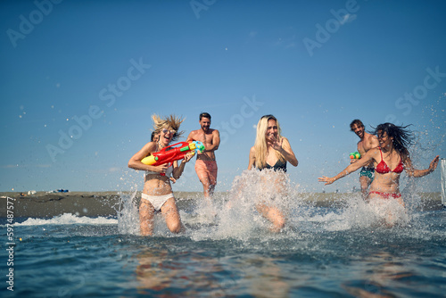 Group of happy friends having a water gun fight