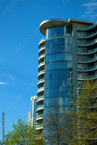 Glass facade. Low-angle view of modern high rise residential building in Kyiv. Blue sky with white clouds in the background. Modern architecture from glass and steel. Concept of real estate in Kyiv