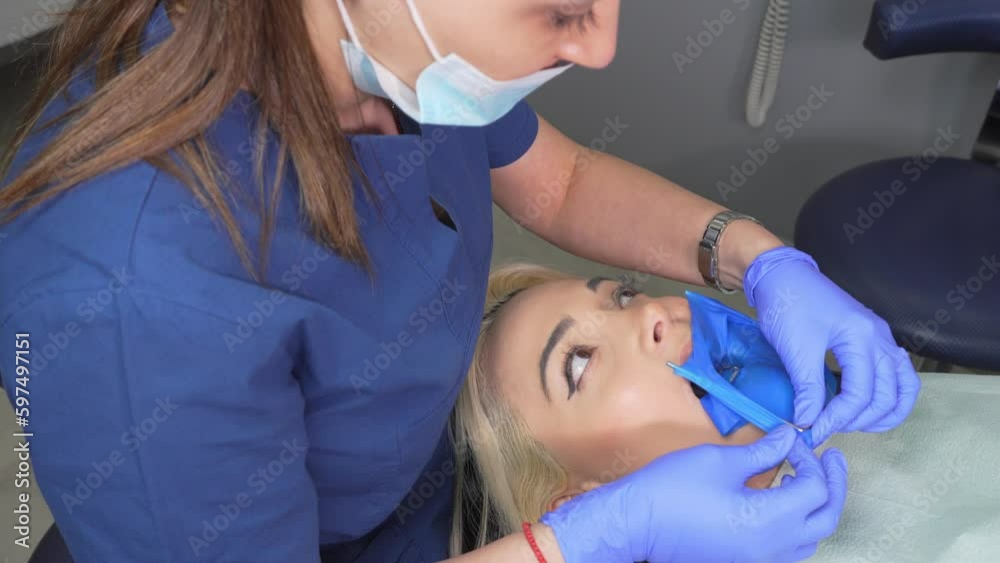 Dentist's hands in gloves with dental punch and cofferdam scarf