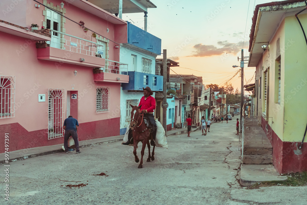Workers on horseback through the streets of Trinidad in Cuba at sunset
