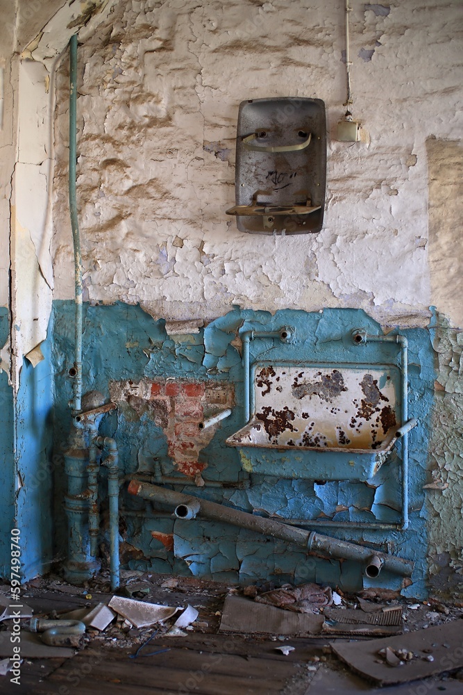 Rusty basin and pipes in an abandoned building with blue painted wall