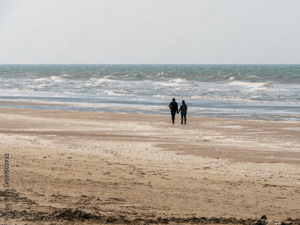 Couple sur une plage de sable regardant la mer agitée Couple sur une plage de sable regardant la mer agitée
