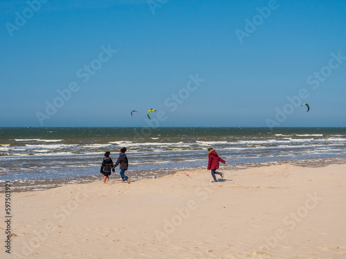 Enfant courant sur la plage avec kitesurf en fond