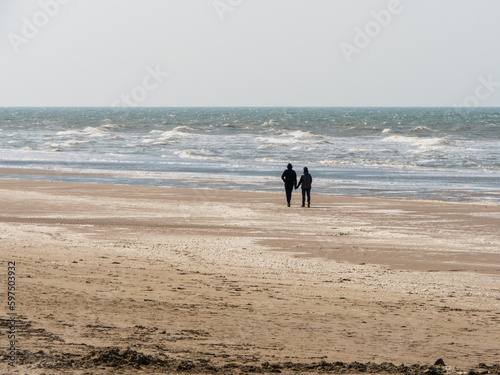 Couple sur une plage de sable regardant la mer agitée 