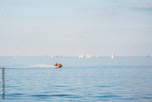 Man riding water motorcycle on Lake Ontario. Sunny day, many yachts and sailboays in the background out of focus. Summer sports and activities concept. Space for copy.