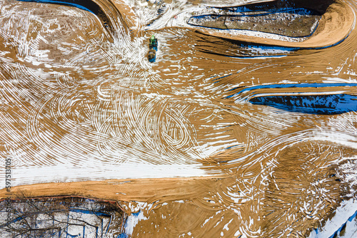 Aerial view of heavy machinery grading a commercial construction site with tire tracks in soil