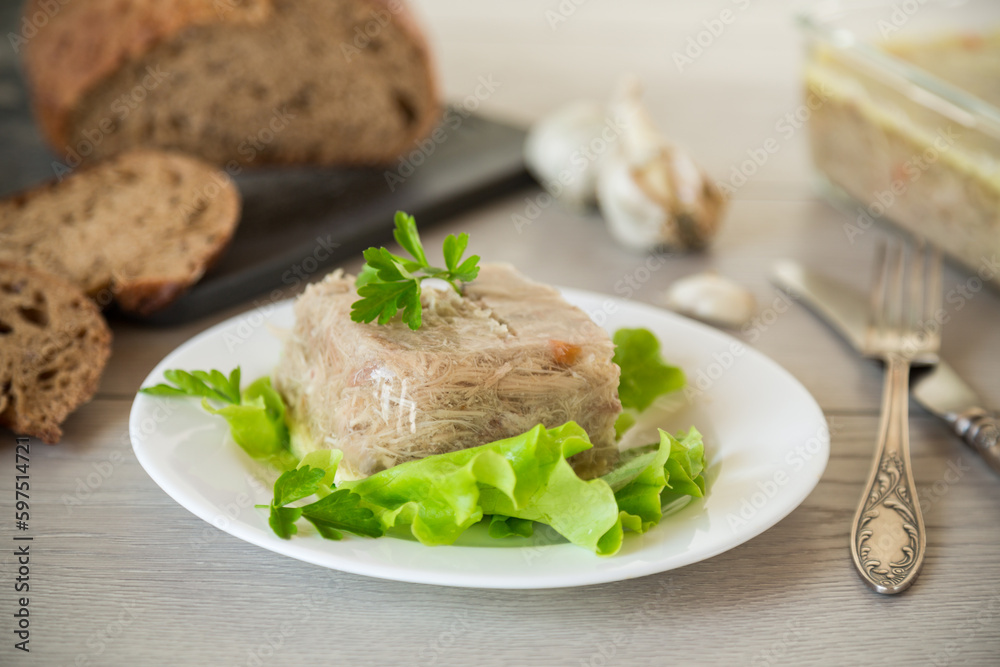 Boiled chicken meat aspic in meat gelatin broth in a plate Boiled chicken meat aspic in meat gelatin broth in a plate