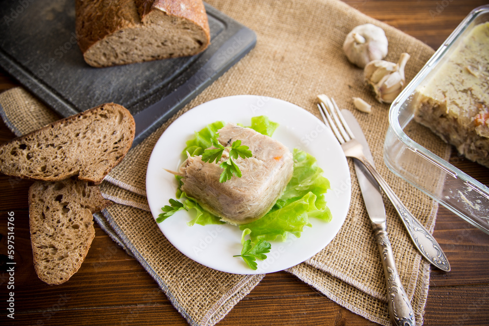 Boiled chicken meat aspic in meat gelatin broth in a plate