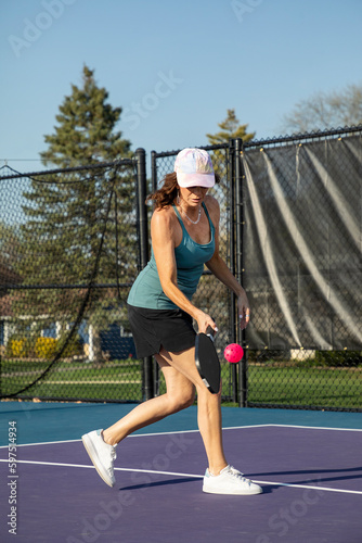 Female Pickleball Player Returning a Pink Ball © pics721