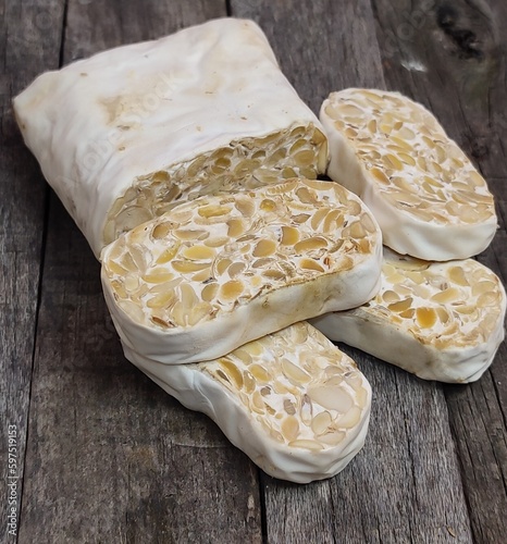 Raw tempeh or tempe. Tempeh slices in wooden plate. Raw soybean seeds Close up . Tempe is Fermented Soy Bean Originally from Indonesia