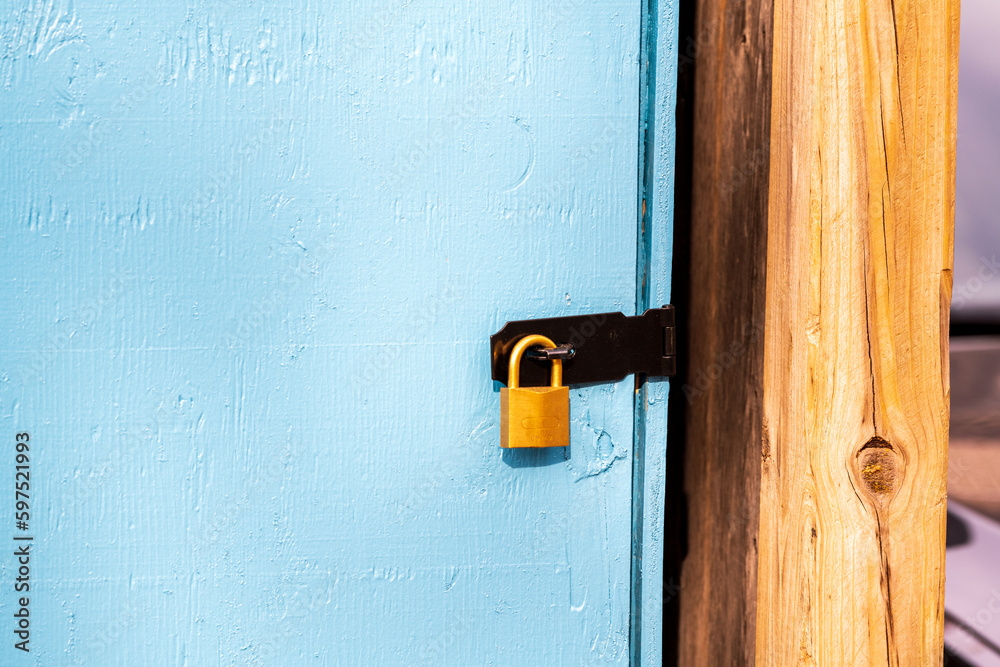 brass padlock securing a black metal hasp on a blue door room for text brass padlock securing a black metal hasp on a blue door room for text