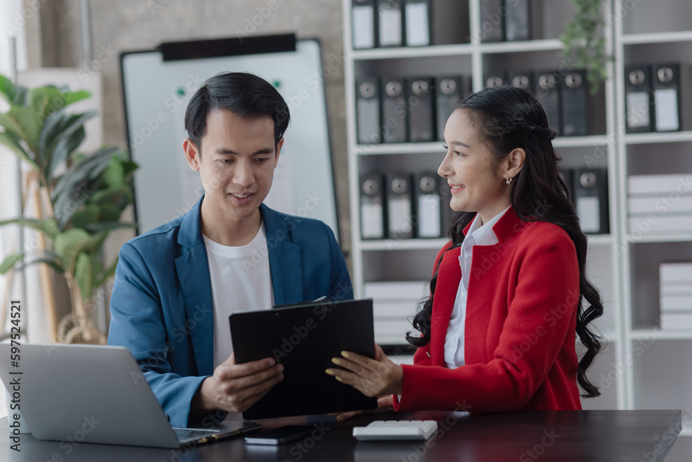 Two employees working at table in a modern office, Asian man and a woman work at office desk, Business campaign result and project planning concept. Two employees working at table in a modern office, Asian man and a woman work at office desk, Business campaign result and project planning concept.