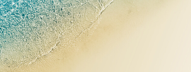 sunny abstract sand beach with transparent clear water from above, natural beach background concept for vacation, holiday, travel and tourism with copy space, closeup top view