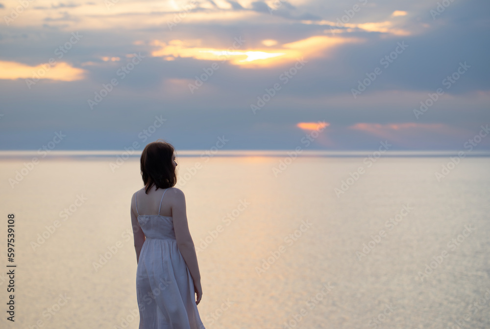 young girl on background sea and sky at sunset