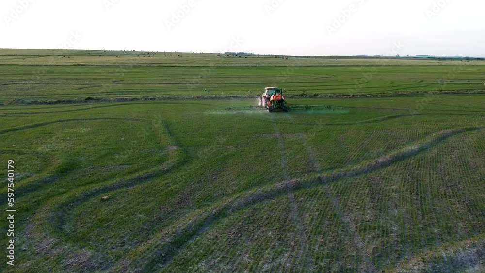 Aerial view agricultural machinery tractor with an irrigation trailer rides through the green field of agricultural crops Aerial view agricultural machinery tractor with an irrigation trailer rides through the green field of agricultural crops