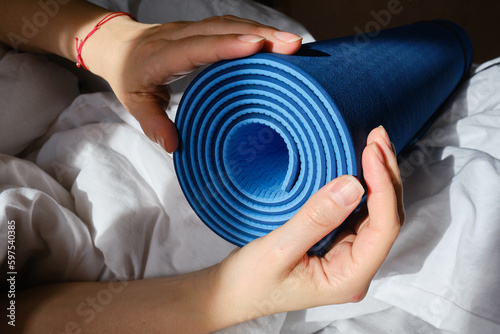 Yoga mat in the hands of a girl close-up on a light background. Health and sport concept 