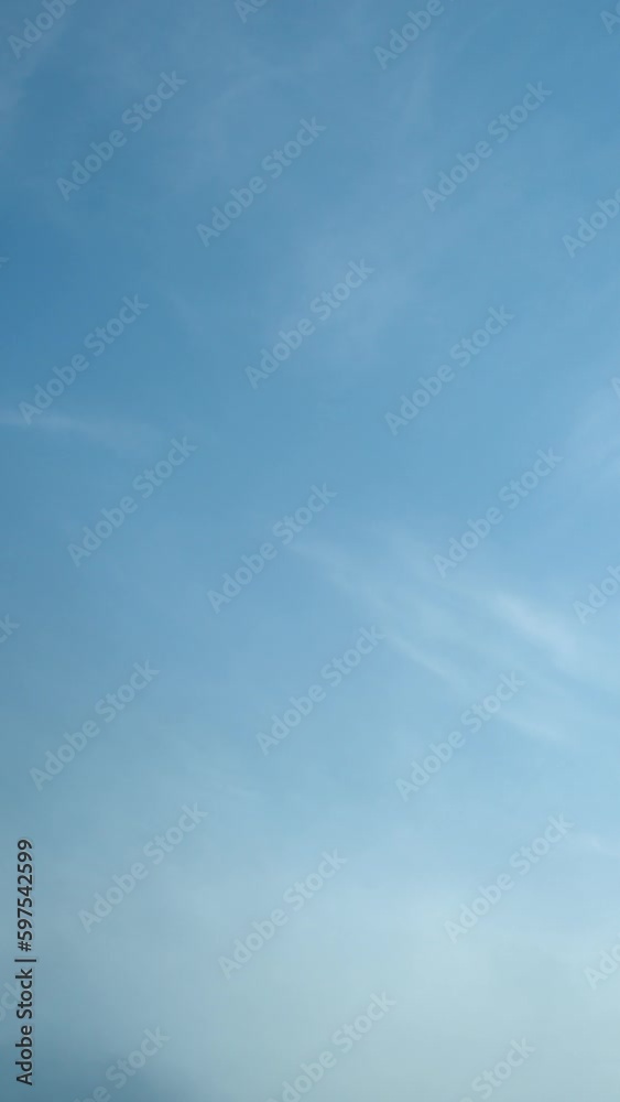 The light and fluffy cirrus clouds slowly move across the serene blue sky. Vertical video. The light and fluffy cirrus clouds slowly move across the serene blue sky. Vertical video.