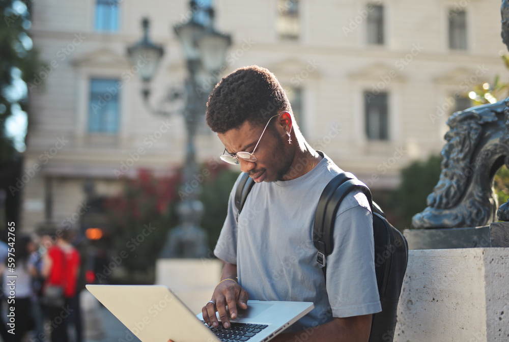 young man uses his computer in the city young man uses his computer in the city