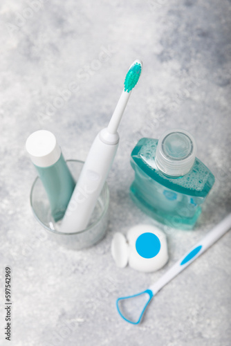 Bathroom with sonic electric toothbrush, toothpaste, mouthwash, dental floss and tongue cleaner against a blue wall. Oral hygiene. Dental care.Dentistry concept.Place for text.Place for copy.MOCKUP