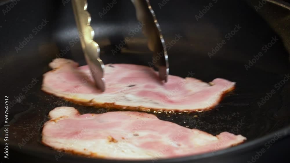 Fry the bacon in a pan. A slice of pork bacon is prepared in its own fat.