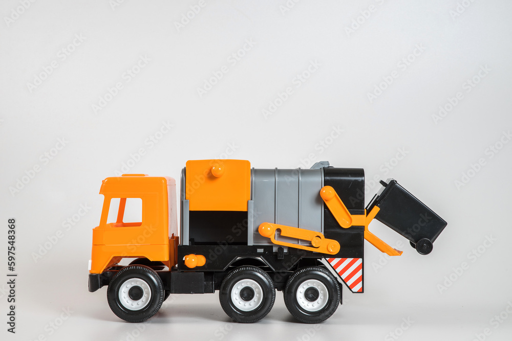 Multi-colored plastic children's toy cars on a white background. Orange garbage truck.