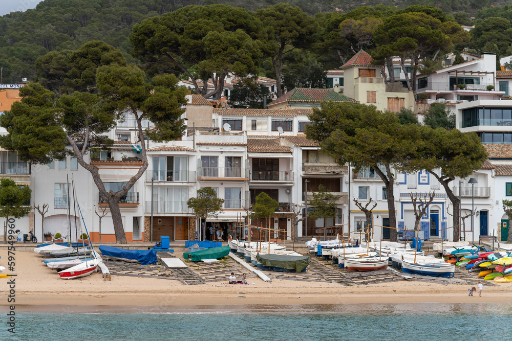 Traditional residence vacation homes on the beach of Costa Brava city. Boats, houses, and the Mediterranean Sea embankment. 