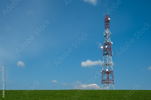 Communication tower on green  field against blue sky photo