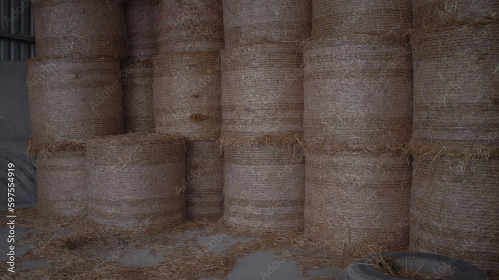 Bales of hay stacked high in rows in hay barn farm building slow motion tracking shot Bales of hay stacked high in rows in hay barn farm building slow motion tracking shot