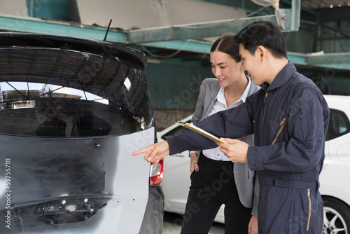 Car mechanic service and maintenance auto body concept. Male mechanic and female car owner customer discuss and checklist repair together during repair process in auto repair shop