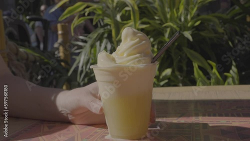 This video shows a spoon digging into a delicious frozen soft serve sorbet dessert with tropical green plants in the background. 