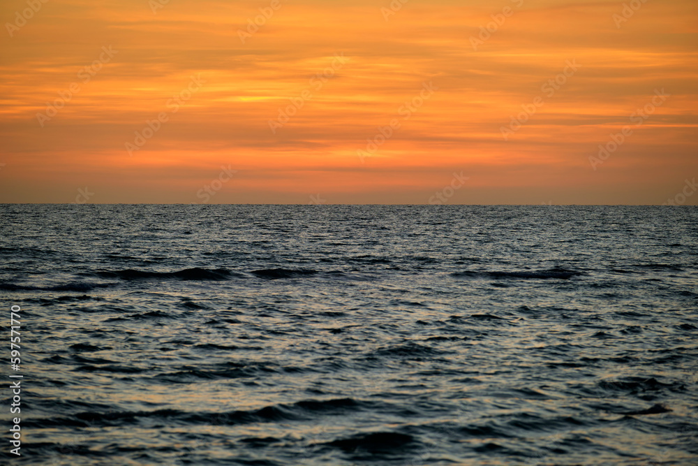 Dramatic red ocean waves at sunset with soft evening sea dark water