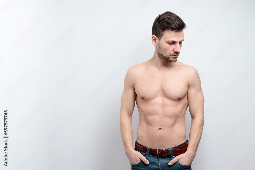 Portrait of handsome shirtless man holding hands in pockets looking side. isolated grey background Portrait of handsome shirtless man holding hands in pockets looking side. isolated grey background