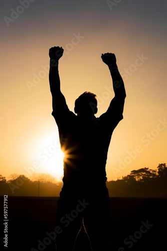 silhueta de atleta comemorando vitória em por do sol 