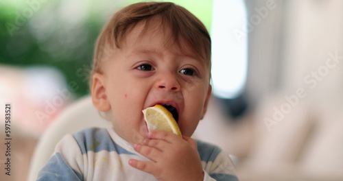 Baby trying lemon for first time, infant toddler face expression grimacing