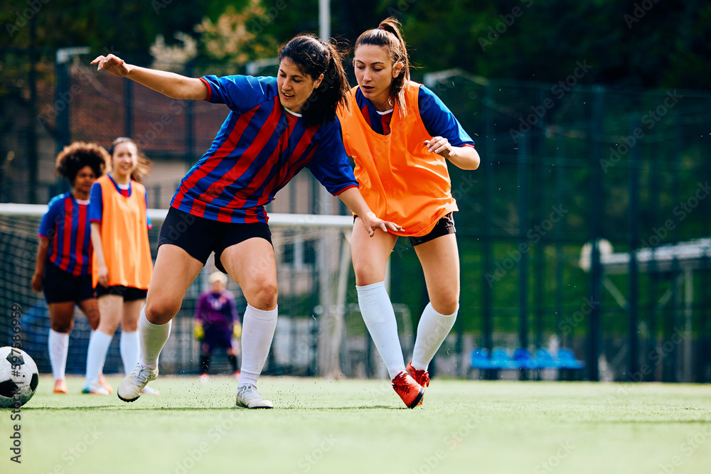 Young athletic women playing soccer on sports training at stadium.