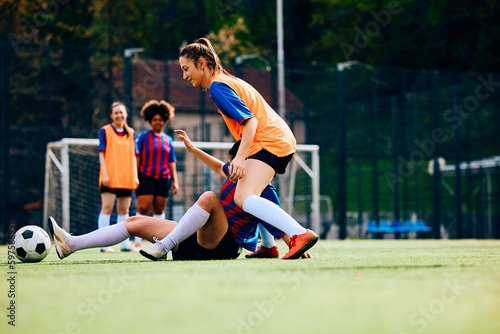 Soccer player fouls her opponent during practice on playing field.