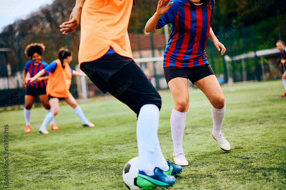 Fototapeta premium Unrecognizable athletic women practicing soccer on playing field.