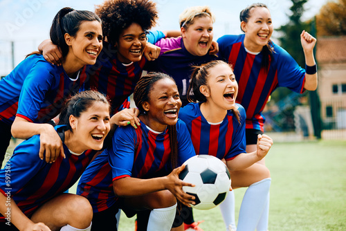 Multiracial team of female soccer players celebrating victory at stadium.