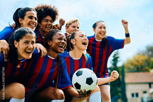 Excited female soccer players shout after winning match on playing field.