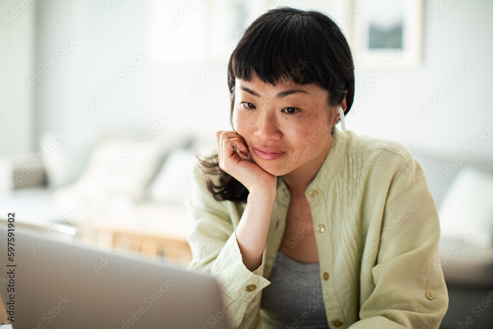 Young Japanese Woman working on a laptop in the kitchen Young Japanese Woman working on a laptop in the kitchen