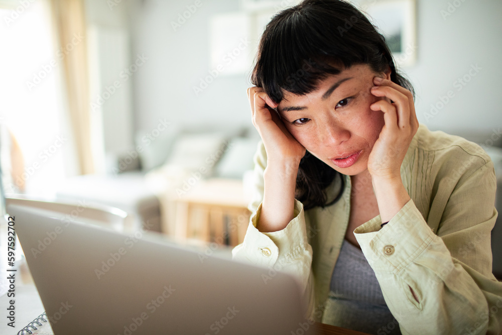 Young Japanese Woman working on a laptop in the kitchen